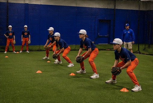 Group of NV Stars players in ready fielding position running a cone drill on the indoor turf